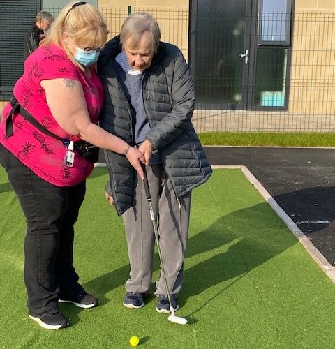 Resident Putting with The Help of Staff Member