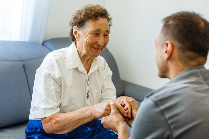 old woman getting visit from grandson in care home