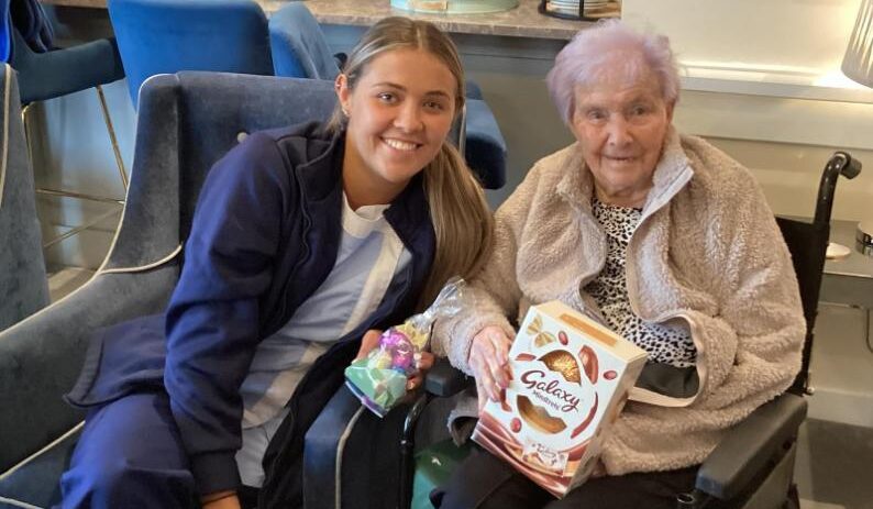 resident with her easter egg and a carer smiling