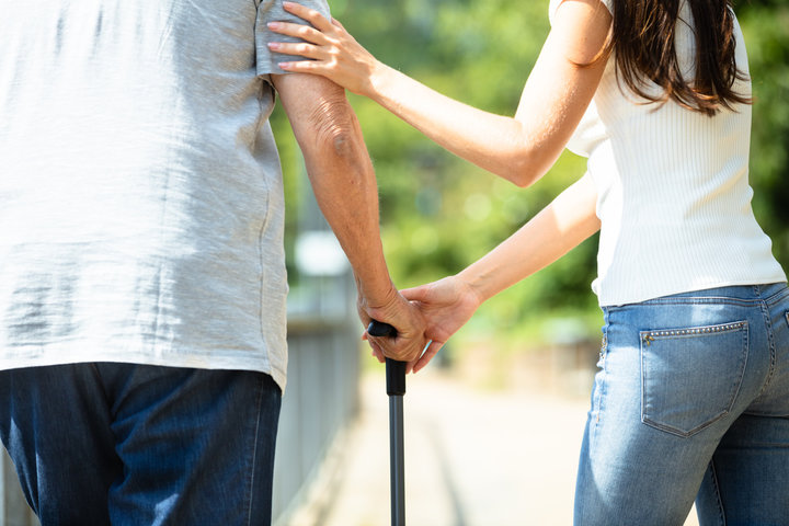 resident getting help walking with stick