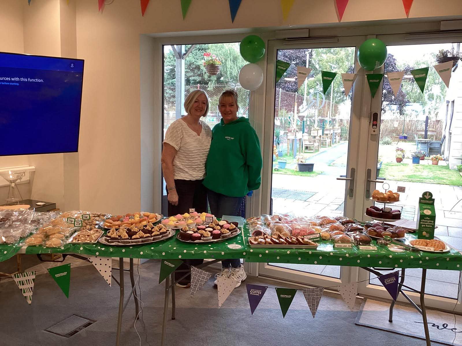 staff smiling at macmillan coffee morning bake sale